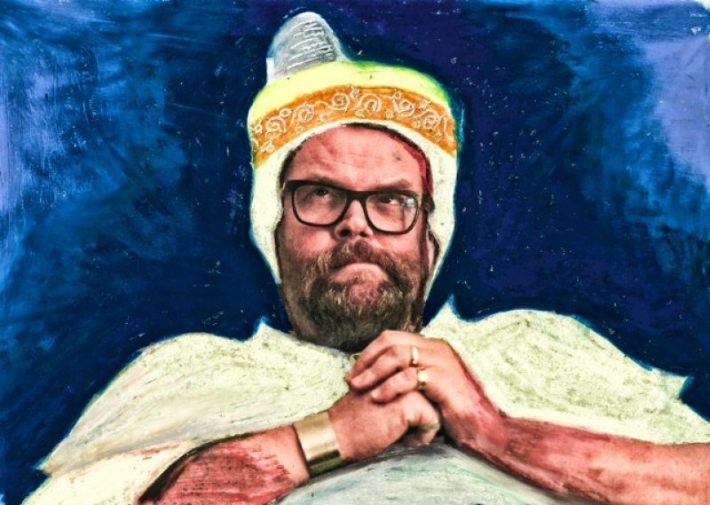 Ein Bild von Jochen Malmsheimer im Stil eines Gemäldes. Er trägt ein weißes Gewand und eine Kopfbedeckung. Hinter ihm ein blauer Hintergrund.